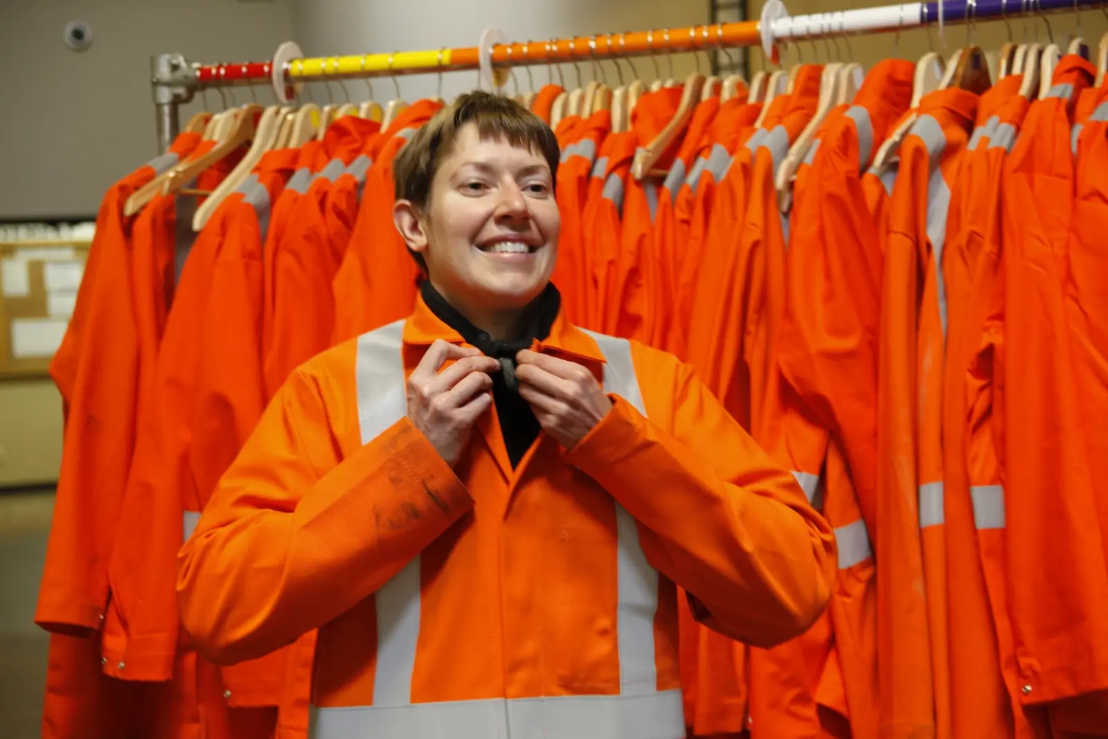 Employee wearing high-visibility safety jacket in locker room