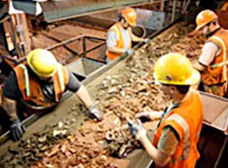 Workers sorting scrap metal on processing line