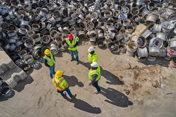 Recycling team meeting near stacked aluminum wheels