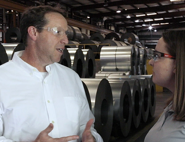 Single-Source Materials Management Solutions Professionals reviewing steel coils in industrial warehouse