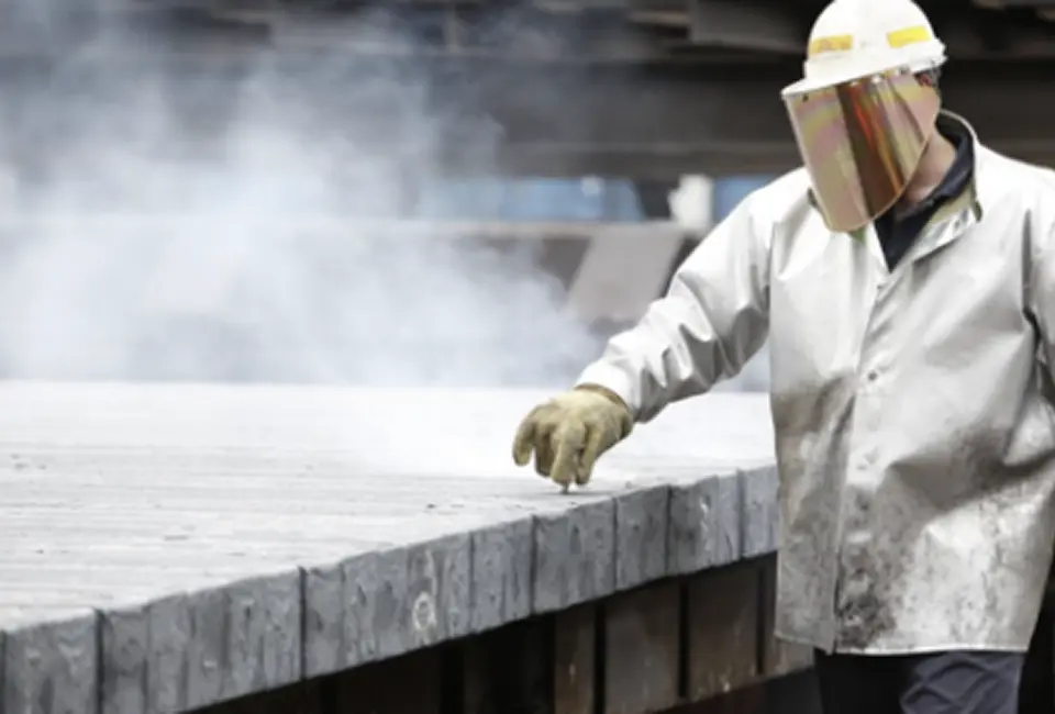 Worker handling manufacturing scrap metal during industrial recycling process