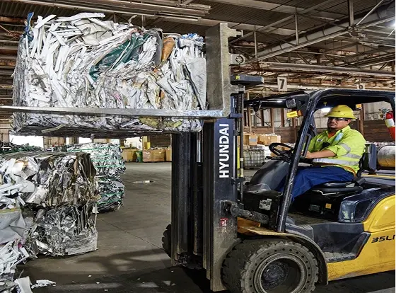 Forklift handling baled scrap metal inside recycling plant