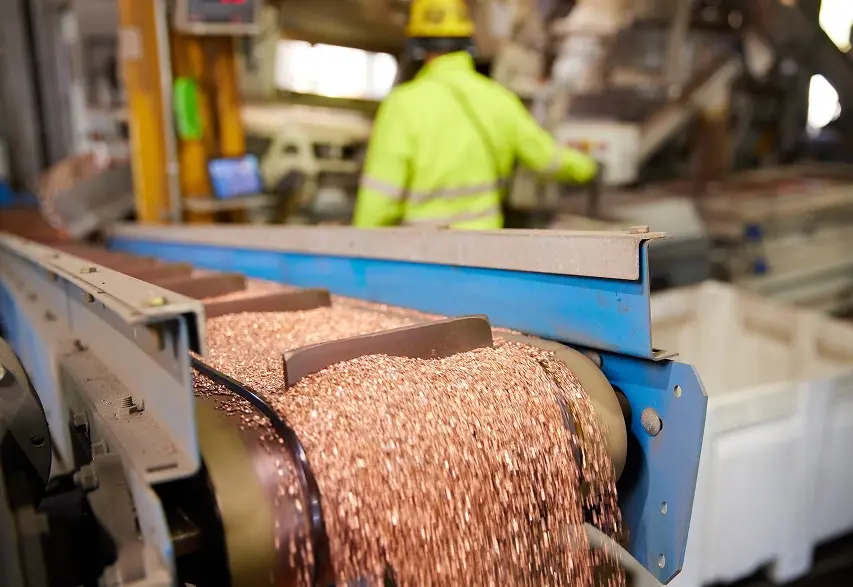Copper scrap moving through an industrial metal processing conveyor