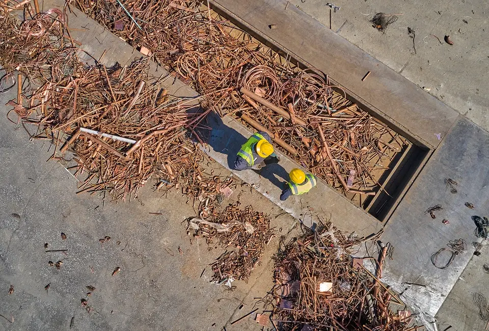 Workers processing copper scrap at recycling facility