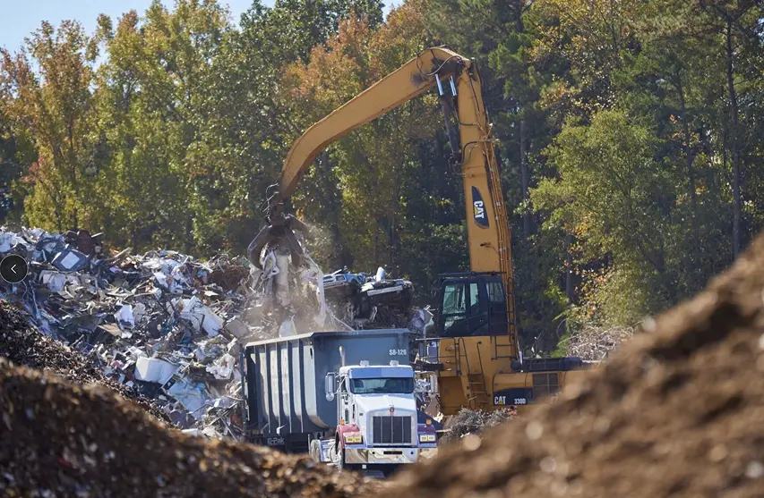 Excavator loading scrap metal for recycling and processing